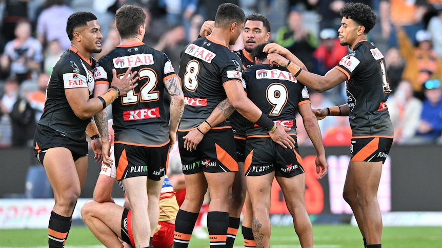 Wests Tigers NRL players celebrate defeating the Dolphins.