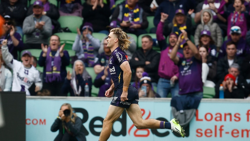 Ryan Papenhuyzen runs onto the field for an NRL game as Melbourne Storm fans cheer behind him.