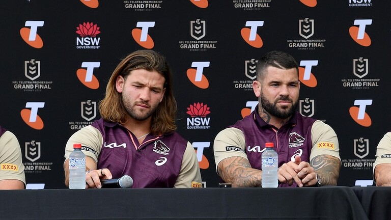 Four palyers and coach sit in front of media wall during a press conference in Broncos gear