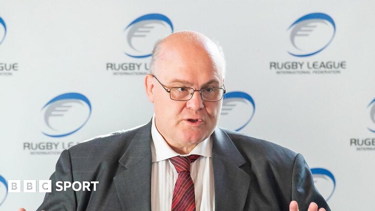 Nigel Wood addressing a room with a Rugby League banner behind him