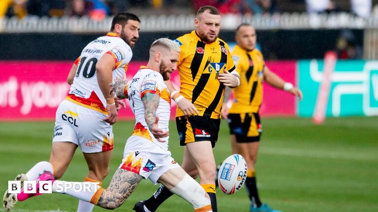 Sam Tomkins kicks the ball away as a Castleford player watches on