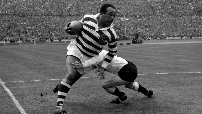 Legendary rugby league star Billy Boston (Wigan) bursts through despite a tackle by I. Watts (Hull) during the Rugby League Challenge Cup Fi