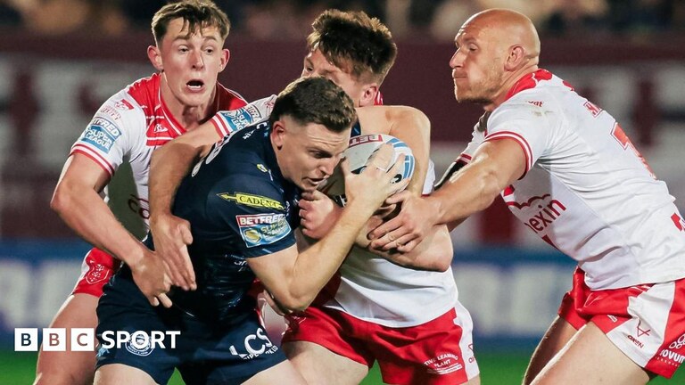 Hull KR winger Tom Davies has the ball in his left arm as he tries to ride the tackles of Jordy Crowther and Sam Powell for Warrington in the 2025 Challenge Cup final.