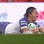 A woman scores a try in wet conditions during an NRLW match
