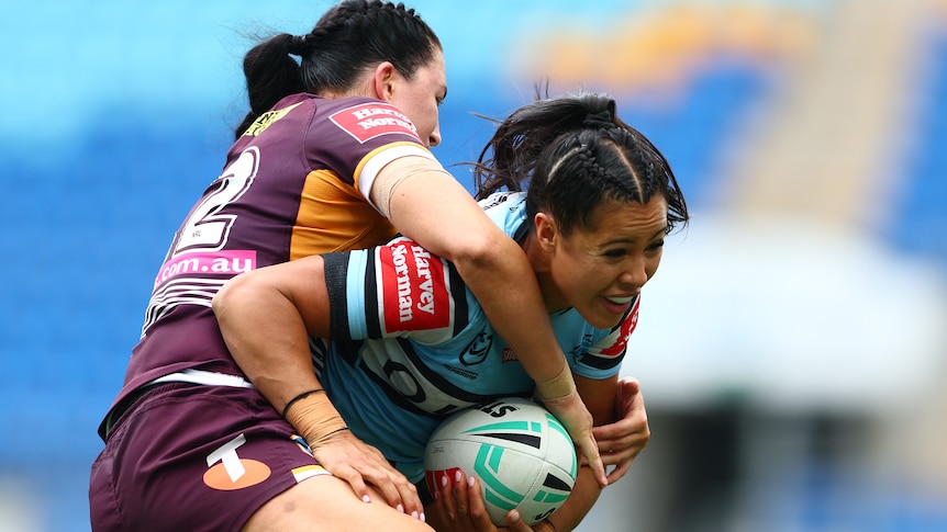 A woman runs the ball during a rugby league match