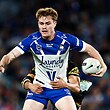 Lachlan Galvin of the Bulldogs is tackled, holding the football in one hand while standing
