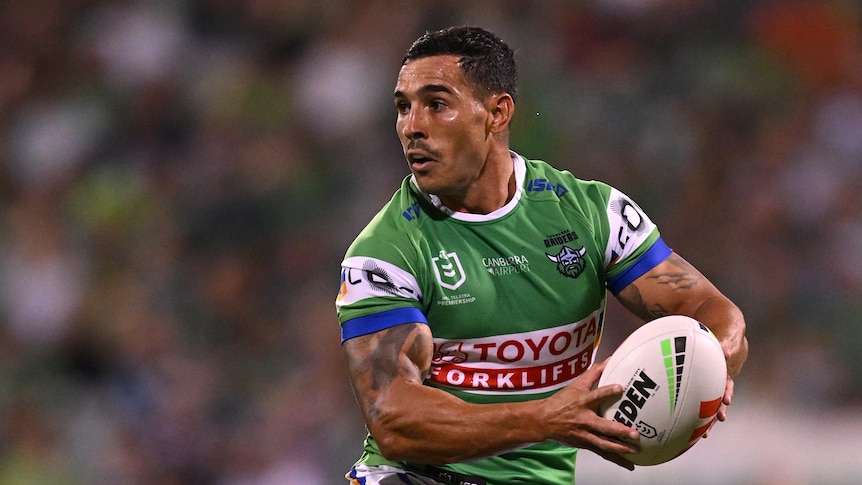 A man looks to pass the ball during a rugby league match