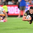 A man scores a try during a rugby league match, while another from the opposite team kneels behind.